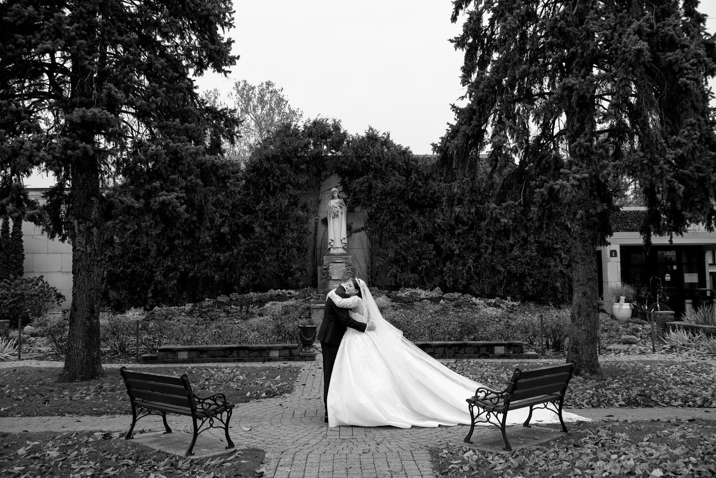 Bride in a cathedral veil on a garden path, black and white