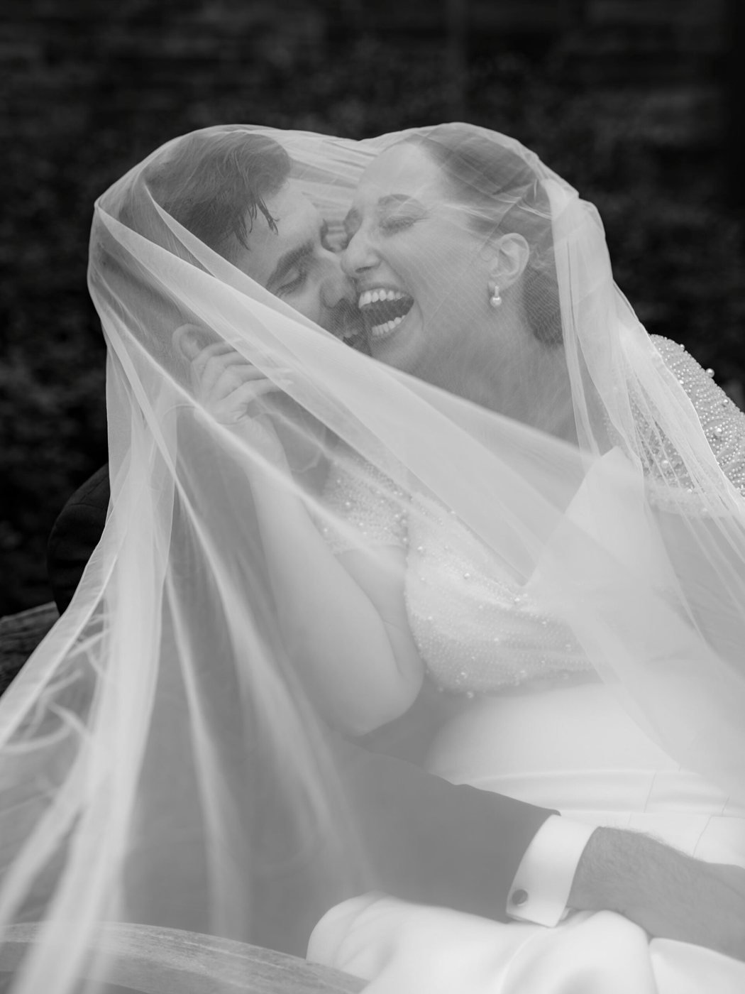 Bride laughing beneath her veil, black and white