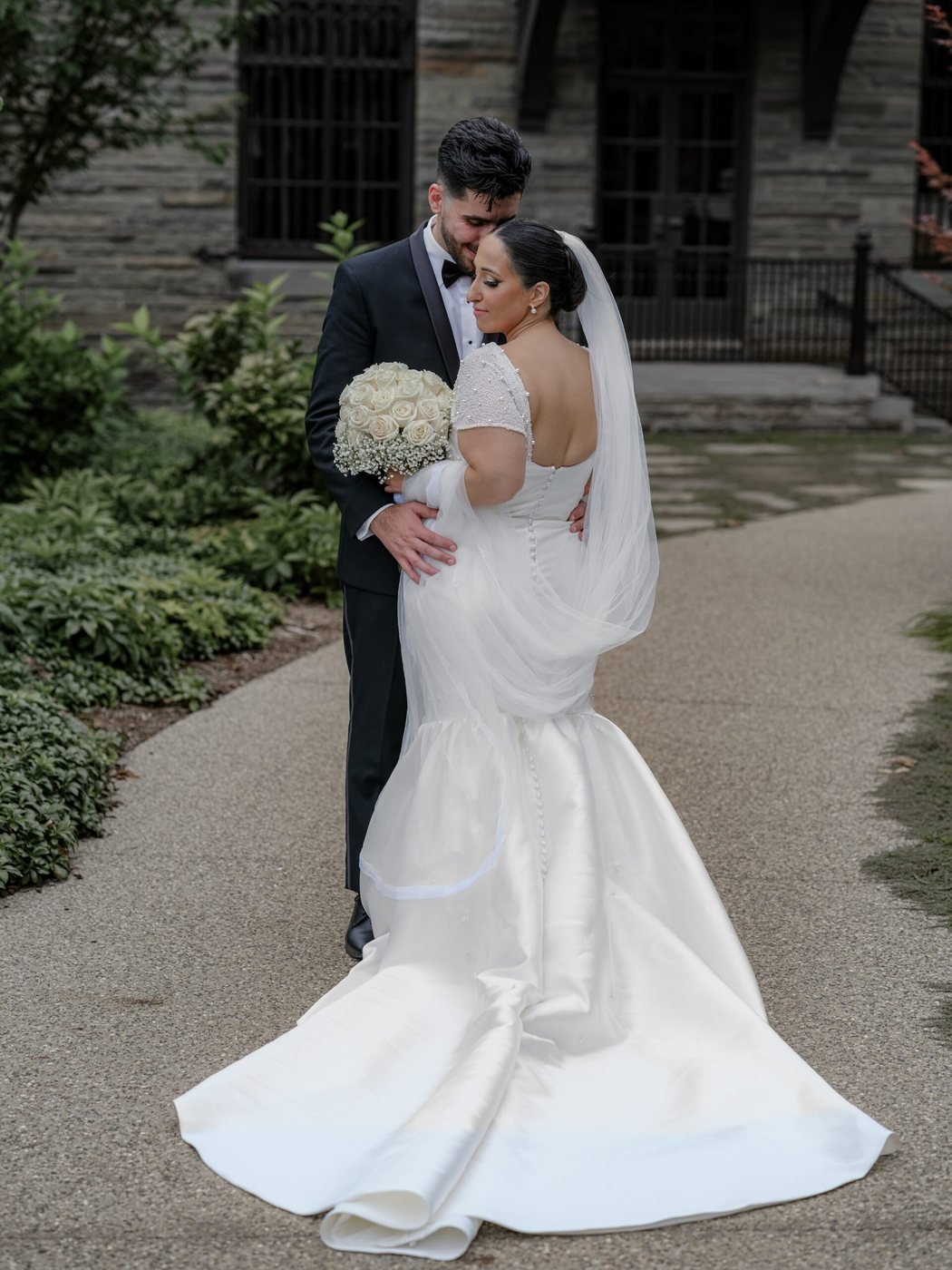 Bride and groom embracing outside a stone chapel